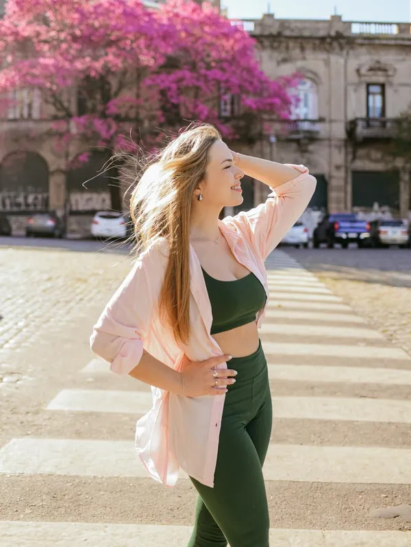Mariana Marchetti sorrindo em uma rua com uma árvore florida ao fundo